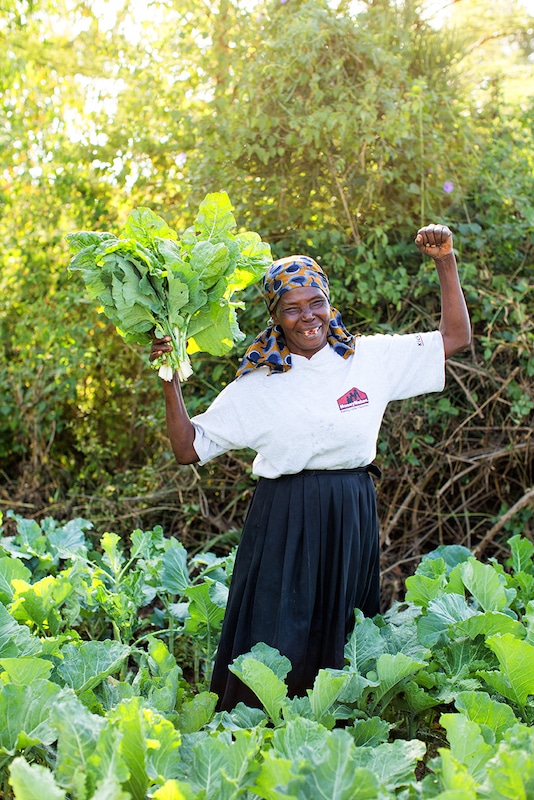 Sarah, a farmer in Kenya, with the crops she's growing with the help of her irrigation pump. like